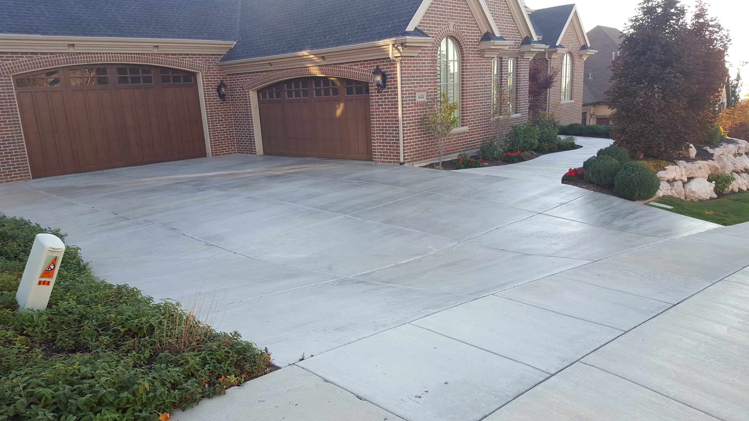Sealed concrete driveway and walkway outside a brick Utah home