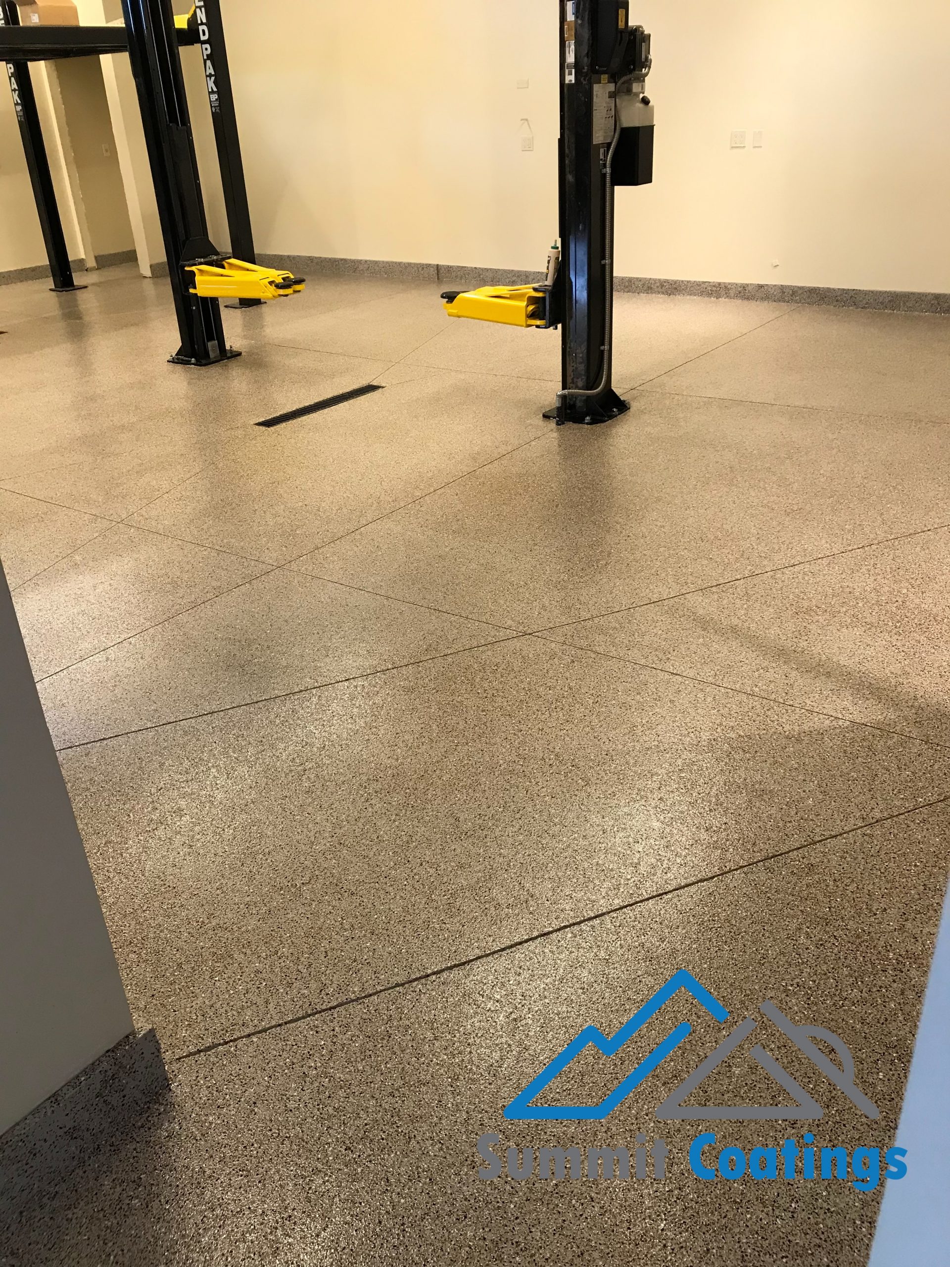 Finished flake garage floor coating beneath vehicle lifts in Utah